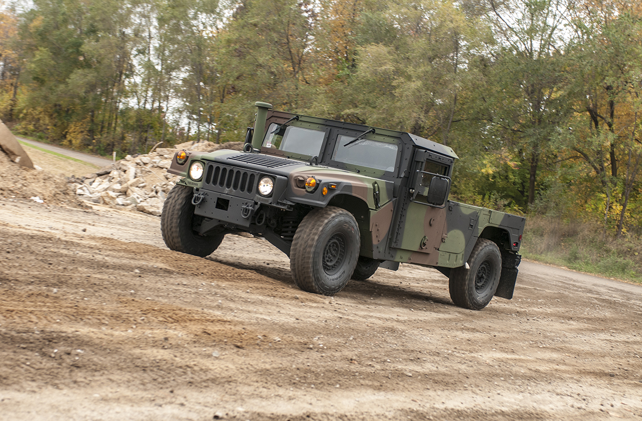 M1152-3 M1152 Humvee with Woodland Camo traveling uphill on a dirtroad