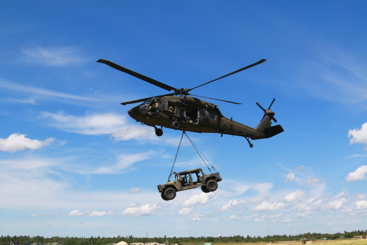 an AM General Humvee is airlifted by a Blackhawk Helicopter