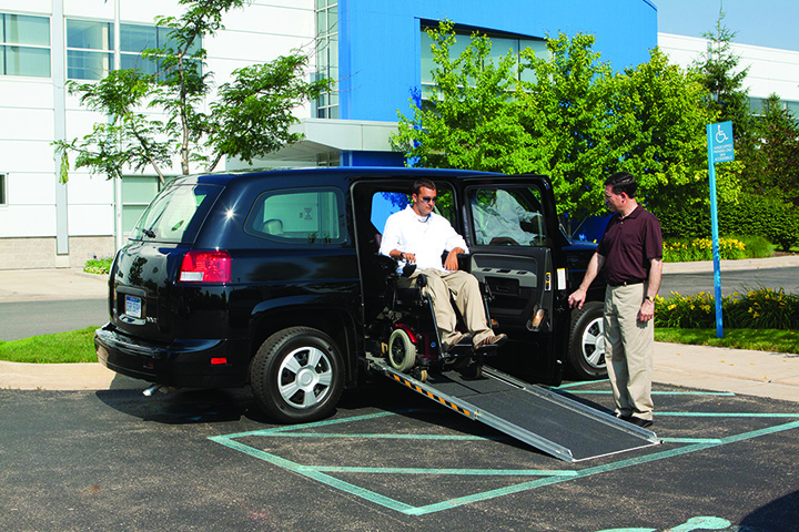 A disabled man uses the handicap ramp of an AM General MV-1